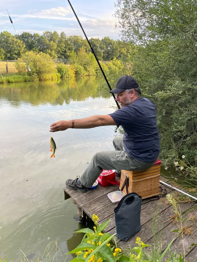 Angler am Ufer des Bahneweihers mit einem gefangenen Fisch